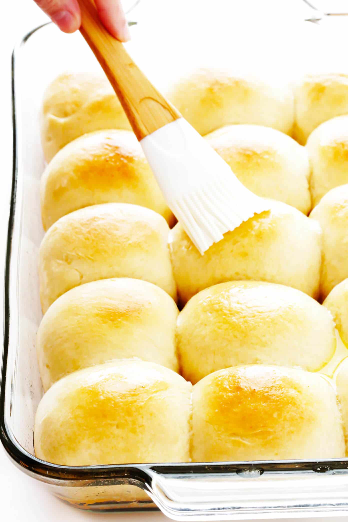 My favorite 1-Hour Soft and Buttery Dinner Rolls recipe is easy to make by hand or with a stand mixer, perfectly soft and fluffy, and so buttery and delicious! Options to make them with garlic, herbs, or extra-cheesy included too! | gimmesomeoven.com #dinner #rolls #buns #side #thanksgiving #christmas #bread #holidays #bake Brushing Dinner Rolls with Melted Butter