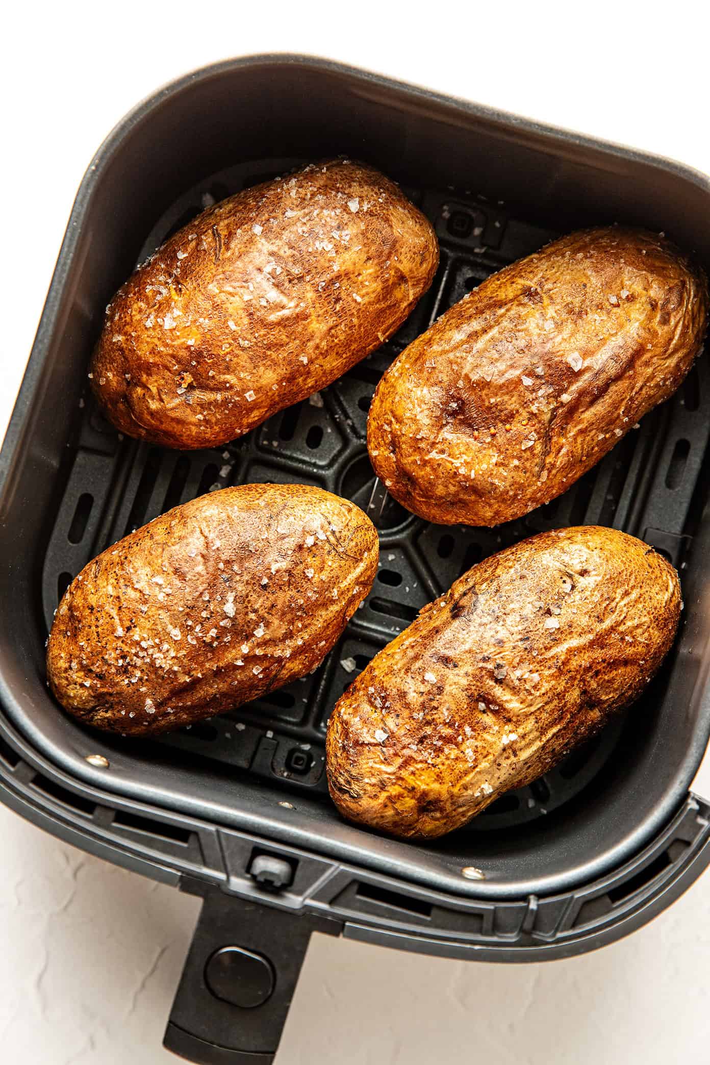 These air fryer baked potatoes turn out perfectly crisp on the outside and fluffy inside in under 45 minutes — the easiest way to make crisp baked potatoes without heating up your oven! | gimmesomeoven.com air fryer baked potatoes with flaky salt