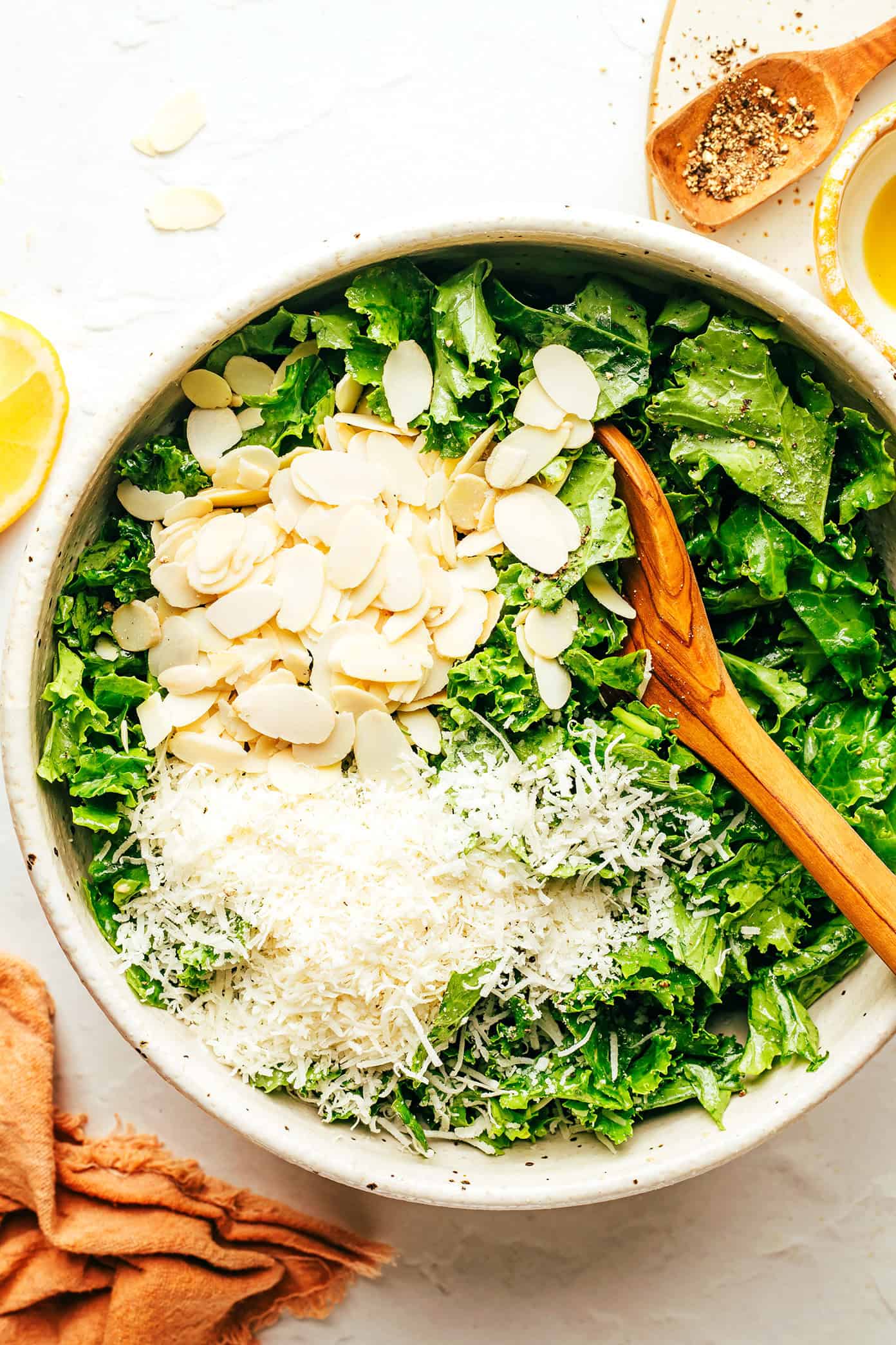 This easy kale salad recipe only takes 5 minutes to make with kale, Parmesan, sliced almonds, lemon, olive oil, and tastes great with just about everything! Feel free to add extra veggies or a protein (such as chicken, shrimp, salmon, etc) if you'd like. | gimmesomeoven.com Kale Salad Ingredients in Bowl