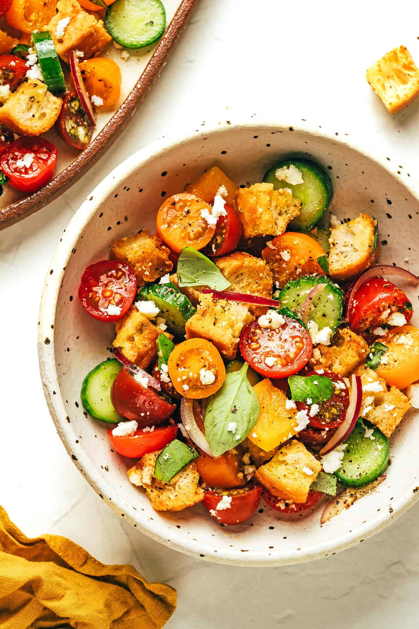 This delicious panzanella salad is easy to make with garlic croutons, fresh cherry tomatoes, cucumber, bell pepper, red onion, feta or mozzarella, and a red wine vinaigrette. The perfect easy dinner recipe for summertime and easy to customize to your liking! | gimmesomeoven.com Panzanella salad in bowl