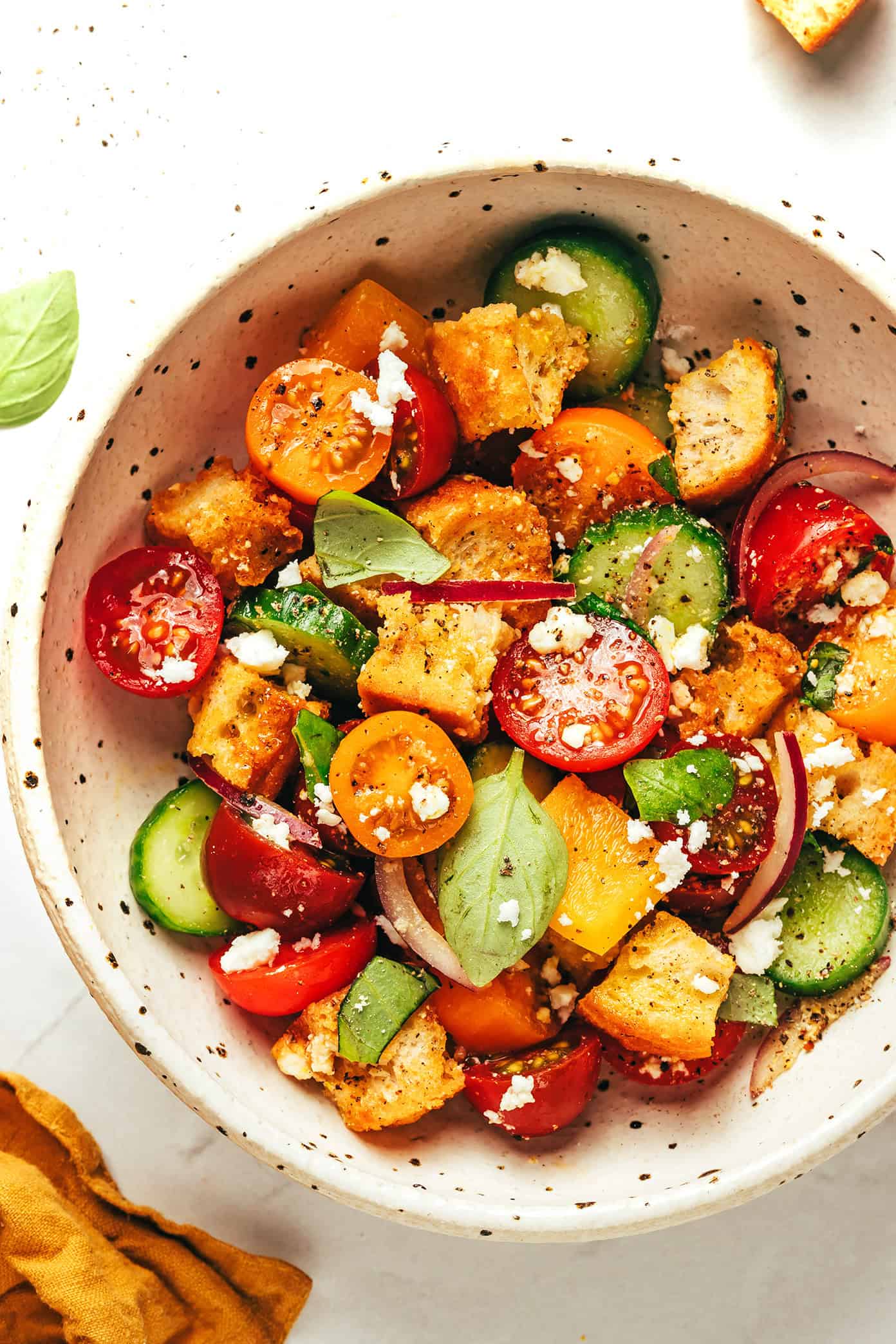 This delicious panzanella salad is easy to make with garlic croutons, fresh cherry tomatoes, cucumber, bell pepper, red onion, feta or mozzarella, and a red wine vinaigrette. The perfect easy dinner recipe for summertime and easy to customize to your liking! | gimmesomeoven.com Panzanella salad closeup
