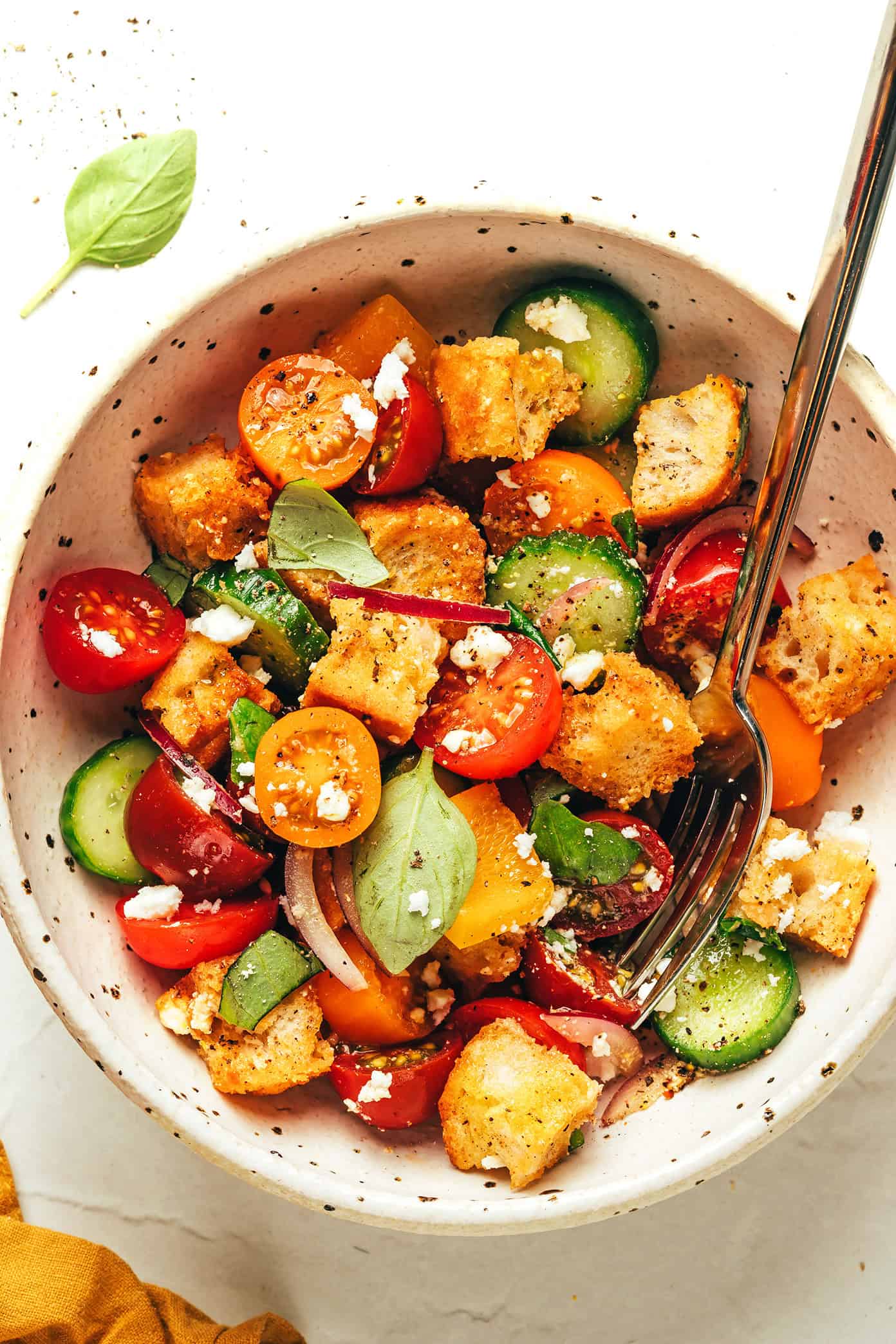 This delicious panzanella salad is easy to make with garlic croutons, fresh cherry tomatoes, cucumber, bell pepper, red onion, feta or mozzarella, and a red wine vinaigrette. The perfect easy dinner recipe for summertime and easy to customize to your liking! | gimmesomeoven.com Panzanella