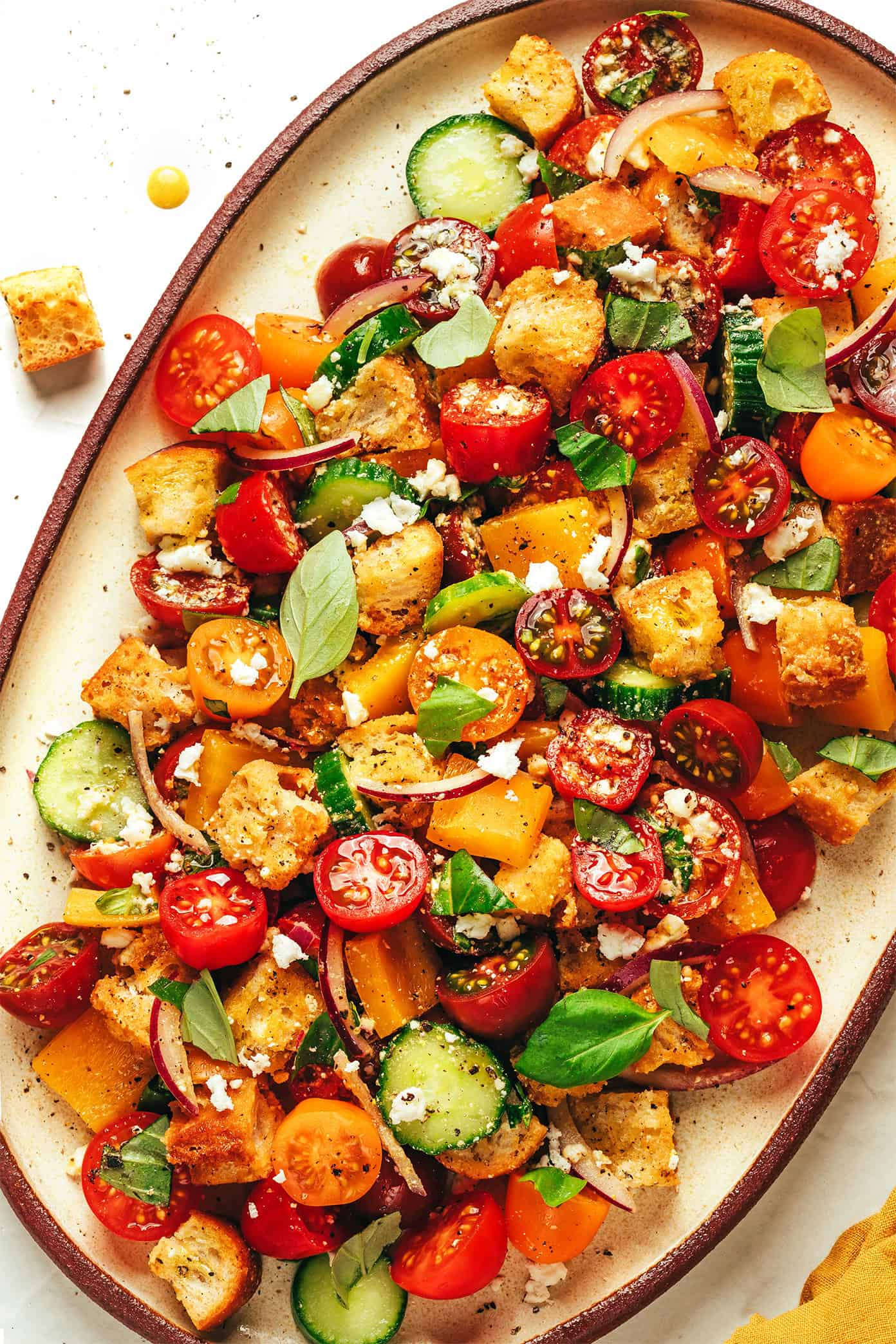 This delicious panzanella salad is easy to make with garlic croutons, fresh cherry tomatoes, cucumber, bell pepper, red onion, feta or mozzarella, and a red wine vinaigrette. The perfect easy dinner recipe for summertime and easy to customize to your liking! | gimmesomeoven.com Panzanella salad